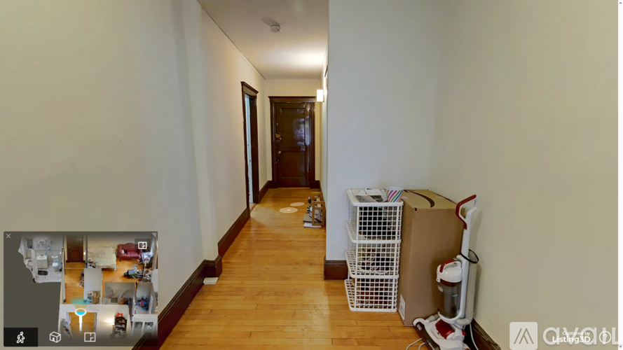 A hallway with a white wall and a brown door.