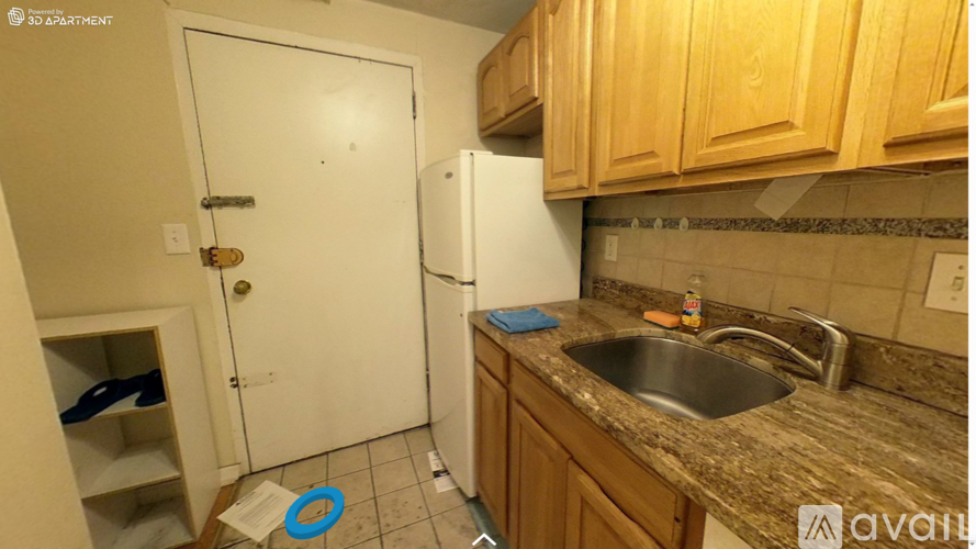 A kitchen with a white door, a sink, and wooden cabinets.