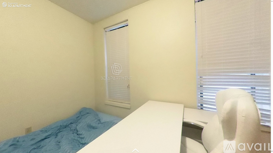 A room with a bed, desk, and window with blinds.