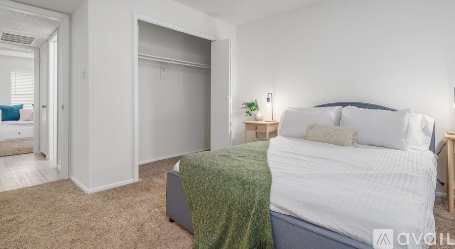 A bedroom with a bed, nightstand, and a window.