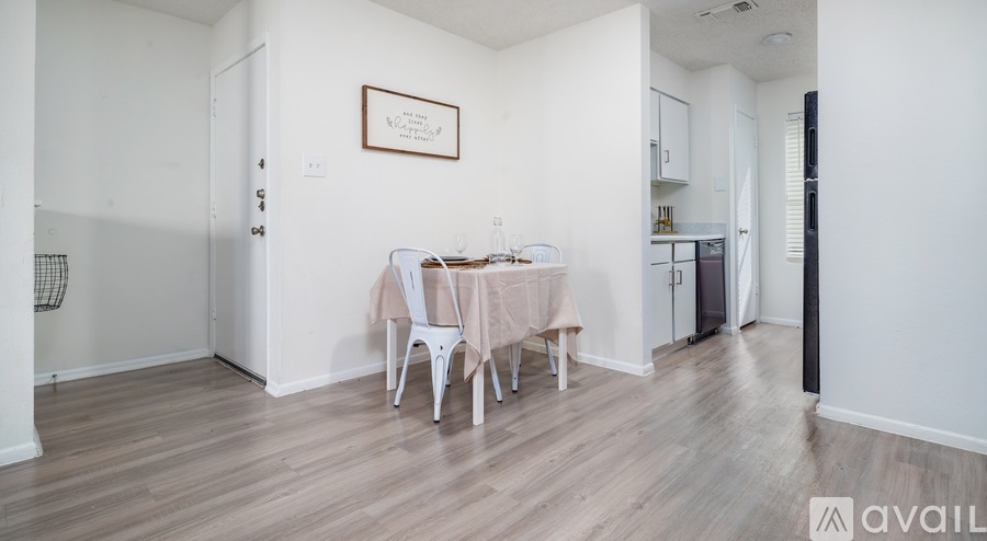 A dining area with a table set for two and a framed picture on the wall.
