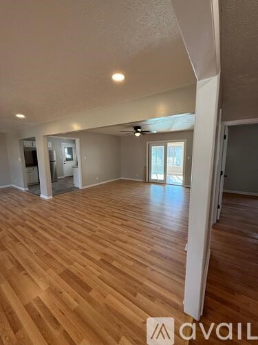 A spacious room with wooden flooring and a ceiling fan.