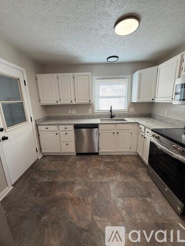 A kitchen with white cabinets and a tiled floor.