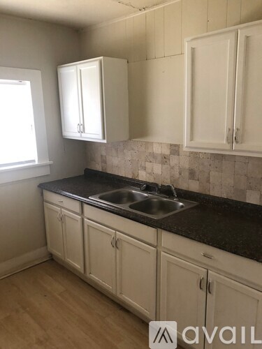 A kitchen with white cabinets and a black counter top.