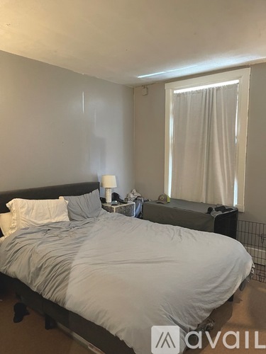 A bedroom with a large bed and a window with curtains.