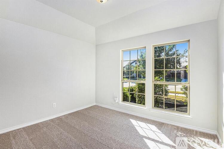 A room with a carpeted floor and a window showing a view of trees and a building outside.