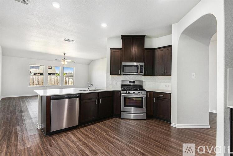 A kitchen with dark wood floors and white walls.