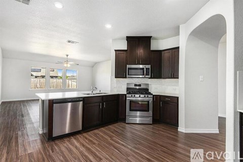 A kitchen with dark wood floors and white walls.
