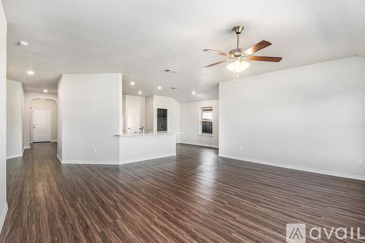 A spacious room with a ceiling fan and wooden flooring.