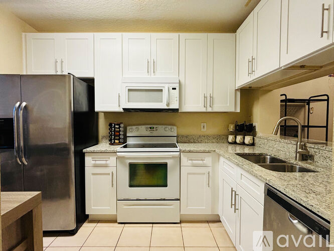 A kitchen with white cabinets and a black refrigerator.