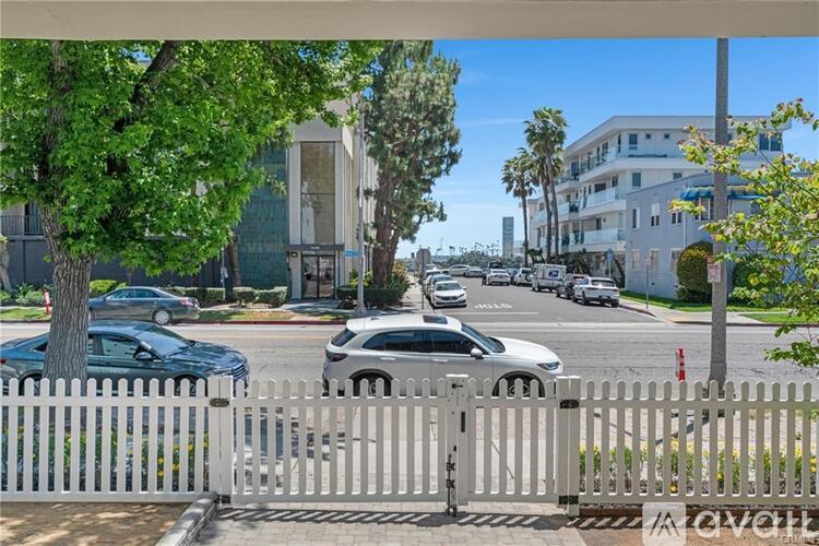 A white fence in front of a street with cars and buildings.