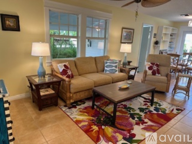 A living room with a couch, chairs, and a rug.