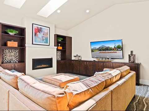 A living room with a large couch and a TV on the wall.