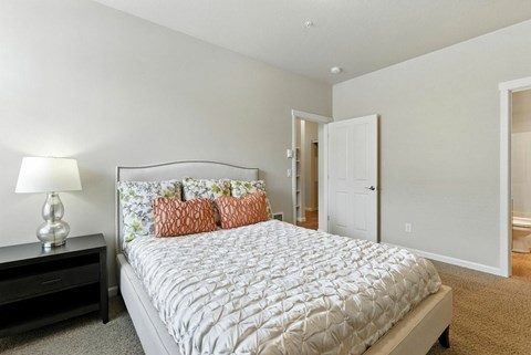 A bedroom with a large bed and a nightstand with a lamp.