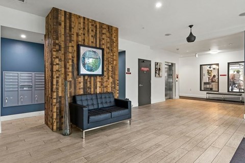 A black couch sits in front of a wooden column in a spacious room.