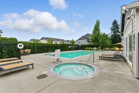 A small pool with a hot tub in the middle of a backyard.