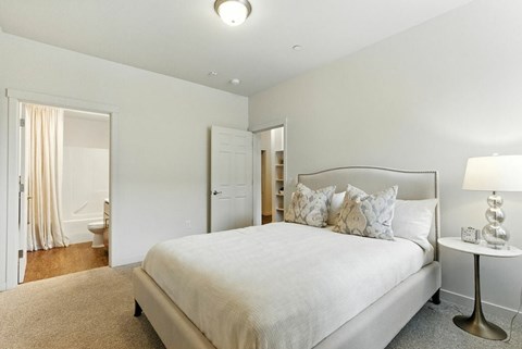 A bedroom with a large bed and a nightstand with a lamp.
