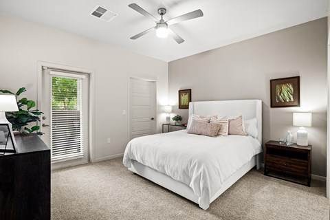 A bedroom with a bed, nightstands, and a ceiling fan.
