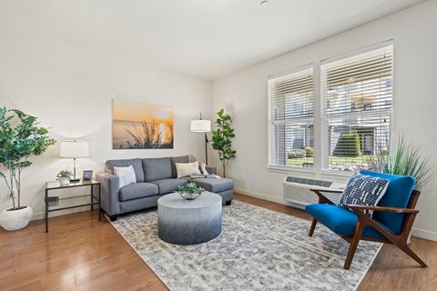 A living room with a grey couch, a blue chair, and a painting on the wall.