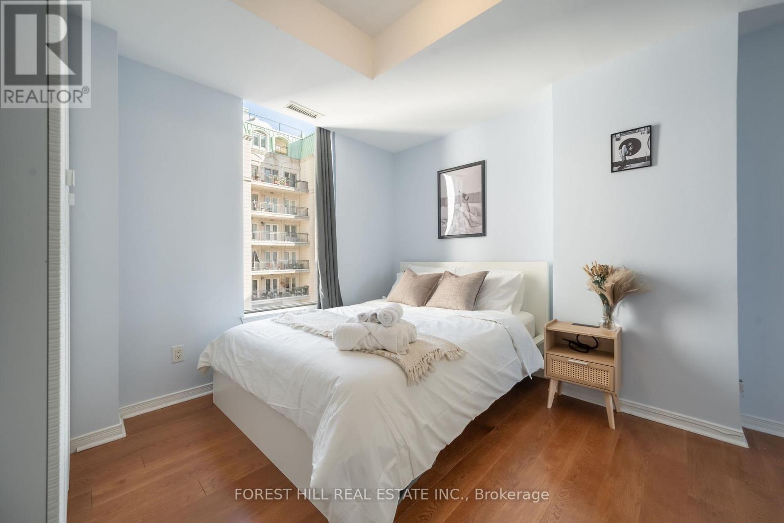 A bedroom with a large bed and a small table with a vase on it.
