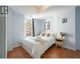 A bedroom with a large bed and a small table with a vase on it.