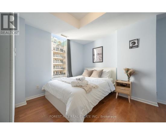 A bedroom with a large bed and a small table with a vase on it.
