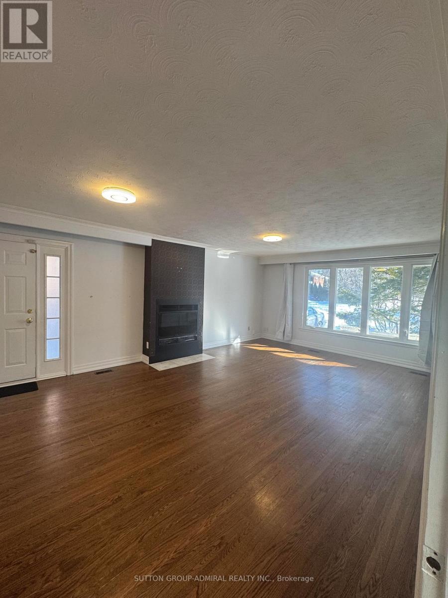 A spacious room with wood flooring and a fireplace.