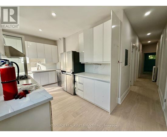A modern kitchen with white cabinets and a wooden floor.