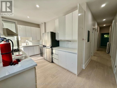 A modern kitchen with white cabinets and a wooden floor.