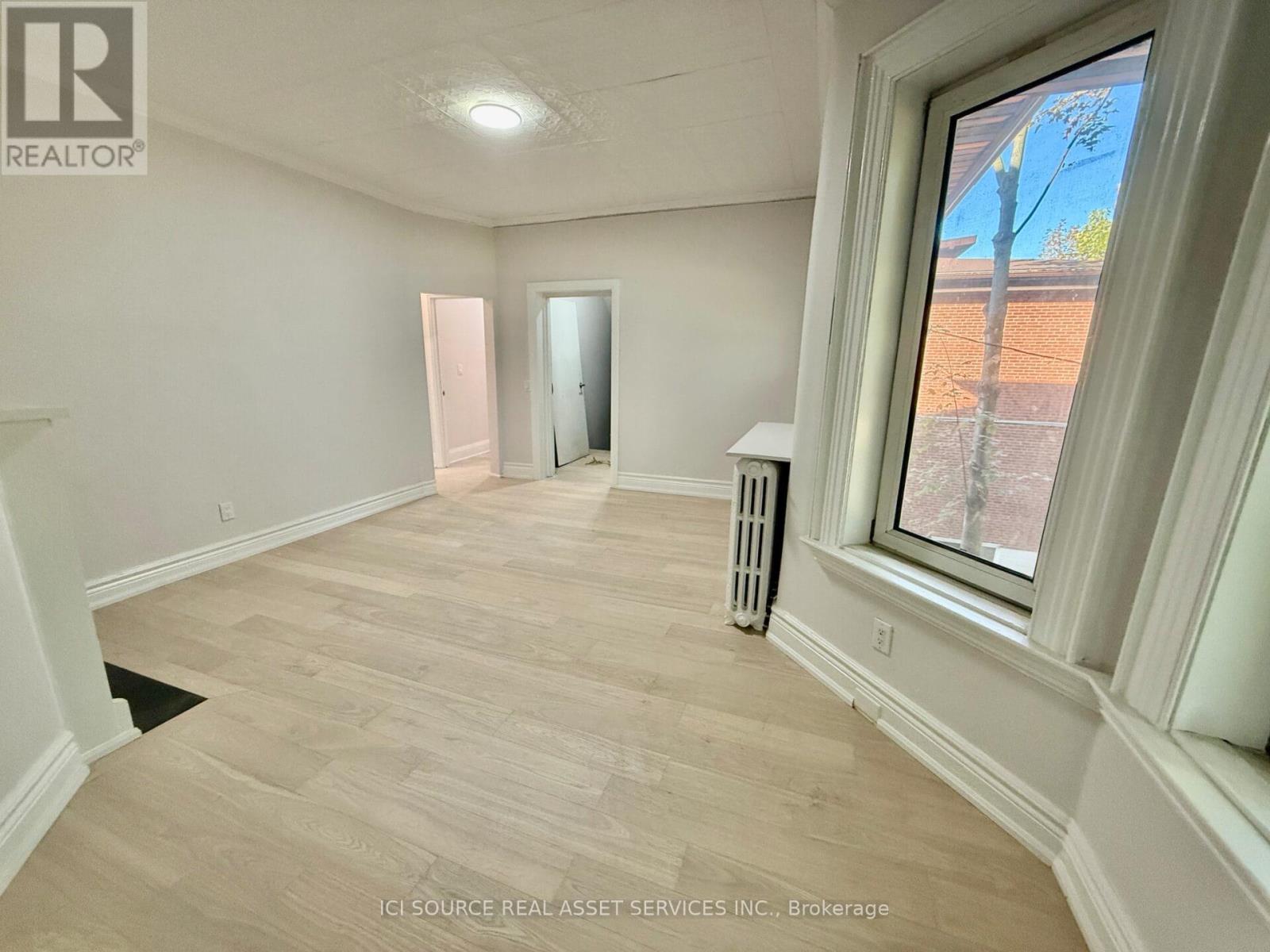 A room with a window showing a view of a tree and a dirt path.