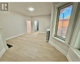 A room with a window showing a view of a tree and a dirt path.