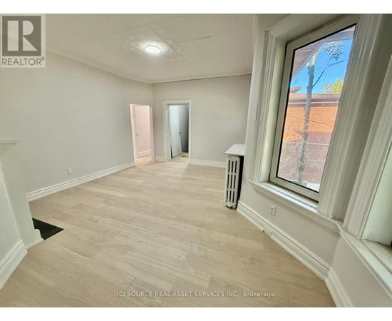 A room with a window showing a view of a tree and a dirt path.