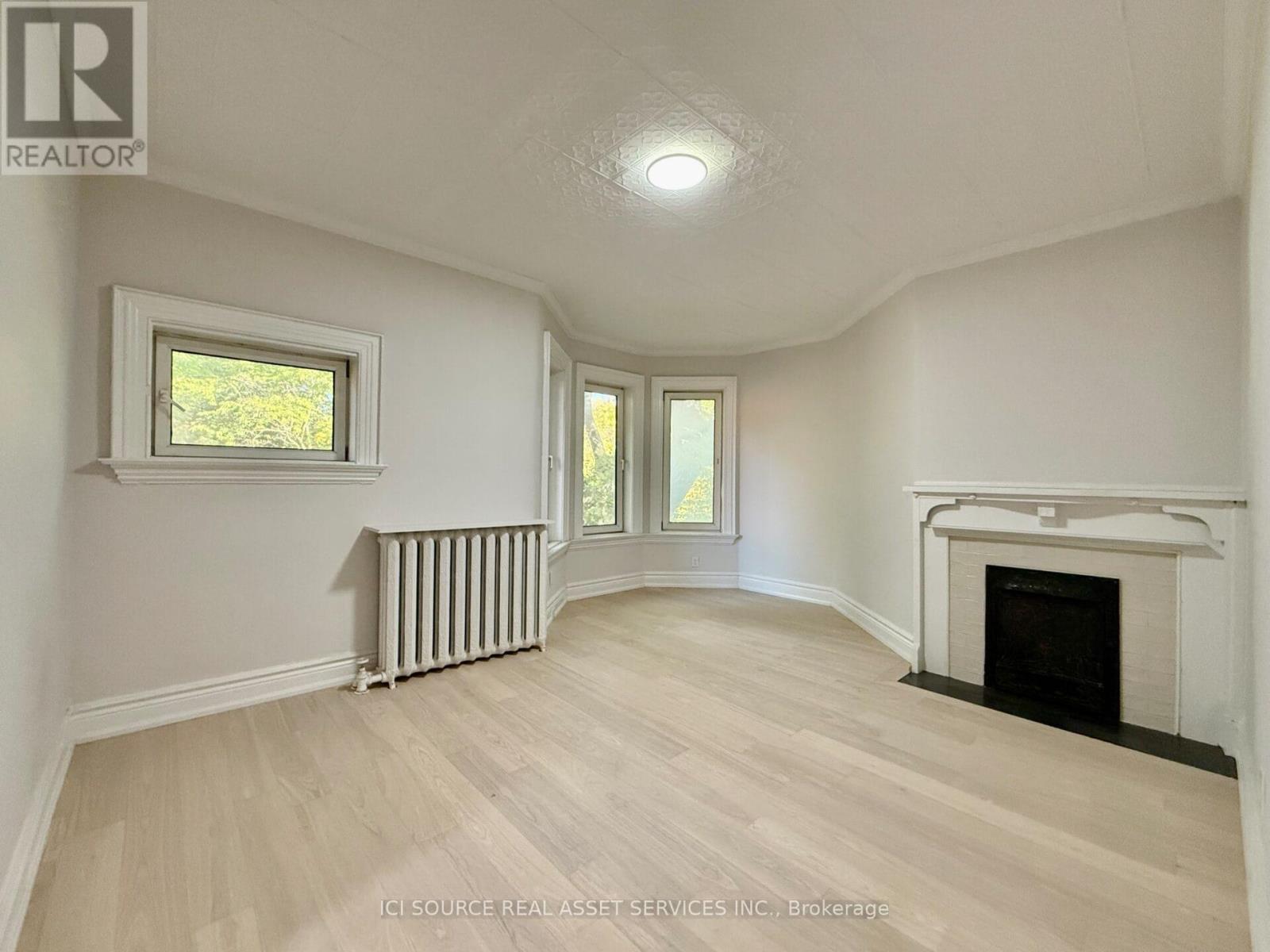 A spacious room with a fireplace and a window.