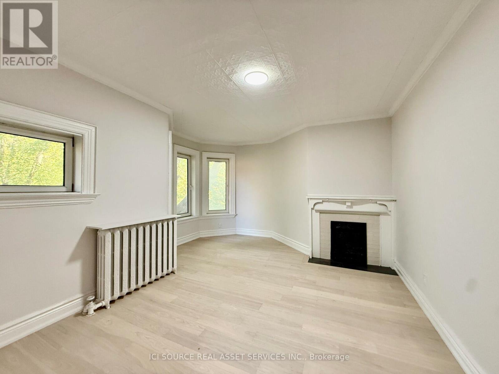 A spacious room with a fireplace and a window.