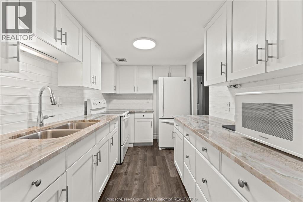 A kitchen with white cabinets and a marble countertop.
