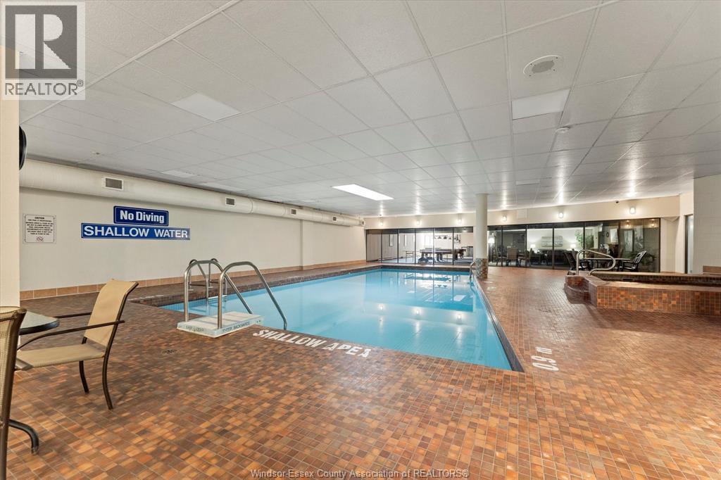 A large indoor swimming pool with a no diving shallow water sign.