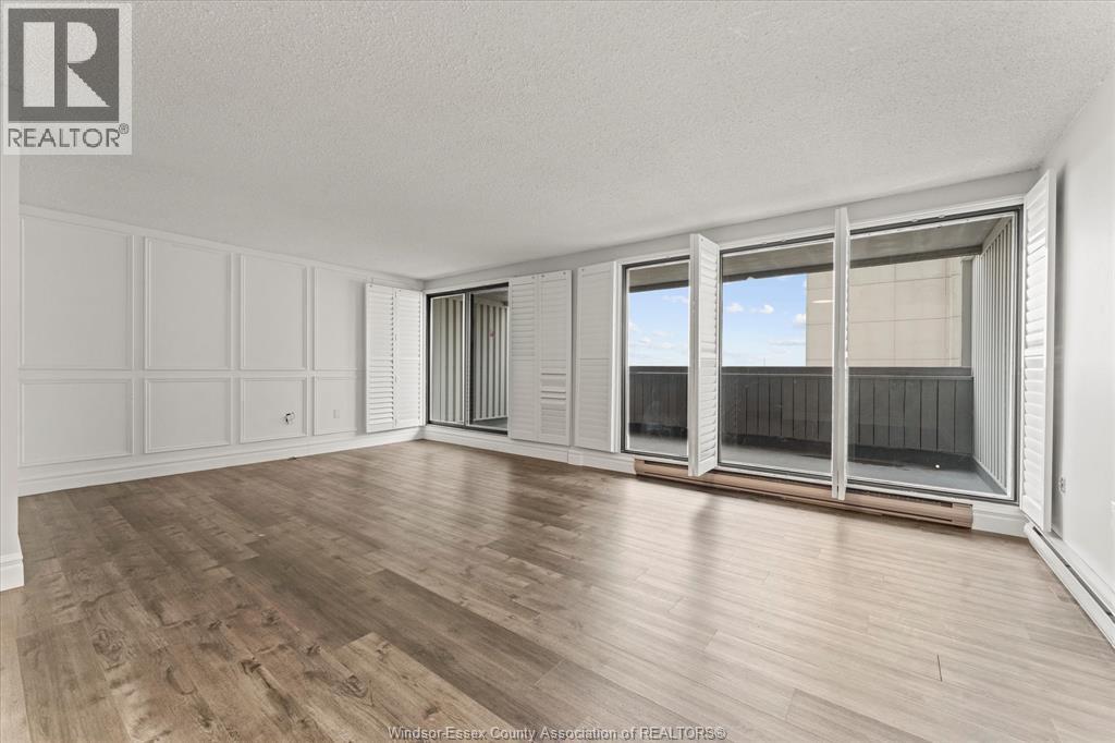 A spacious room with wooden flooring and large windows.