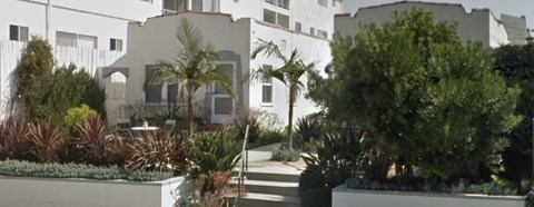 A white building with a garden in front.