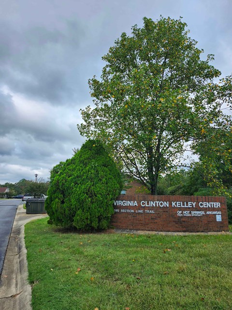 A sign for the Virginia Clinton Kelley Center sits on a grassy area.