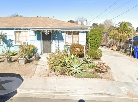 A blue house with a white door and windows, surrounded by a garden.