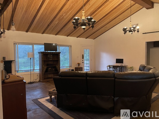 A living room with a brown leather couch and a wooden ceiling.