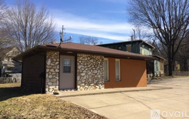 A house with a stone wall and a brown roof is for sale.
