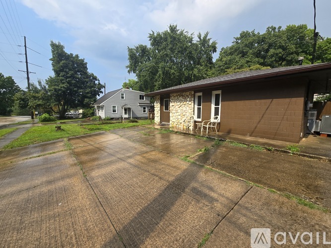 A wet driveway leads to a house with a garage.