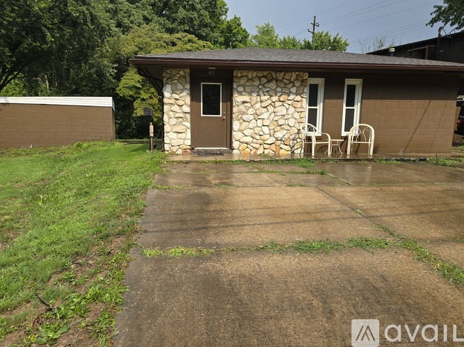 A small house with a stone wall and a brown roof.