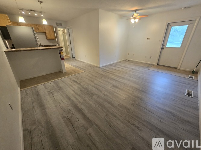 A spacious room with a kitchen area and a ceiling fan.