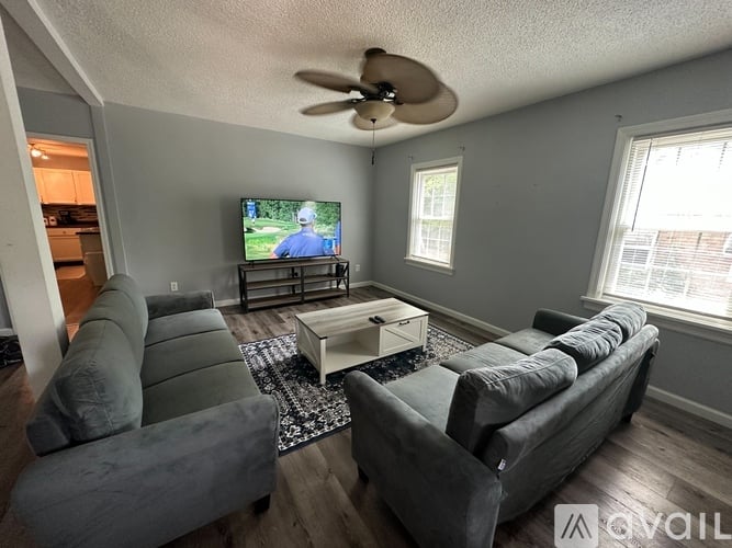 A living room with a grey couch and a television on the wall.