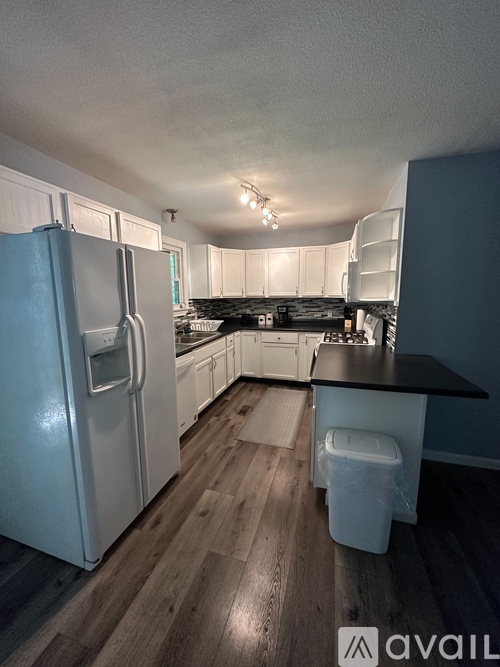 A kitchen with a white fridge and wooden floors.