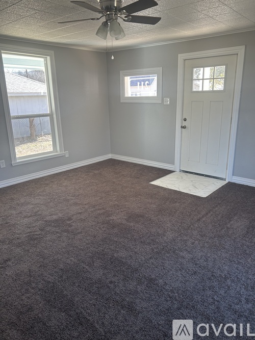 A room with a carpeted floor and a ceiling fan.