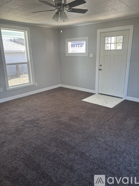 A room with a carpeted floor and a ceiling fan.