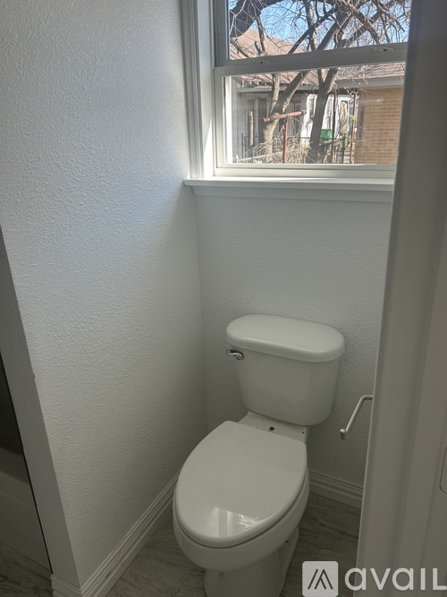 A white toilet in a small bathroom with a window.